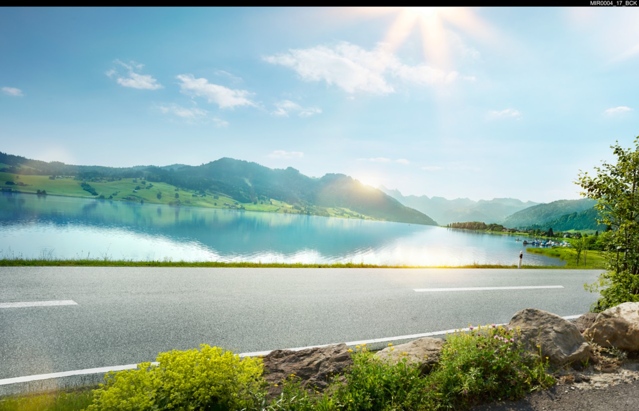 кадър на път минаващ покрай езеро със слънчев планински пейзаж